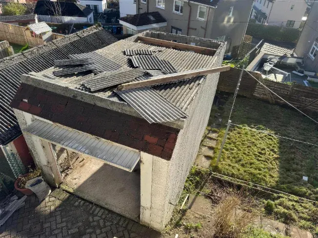 Corrugated asbestos cement sheets being lifted from a domestic garage roof in Edinburgh