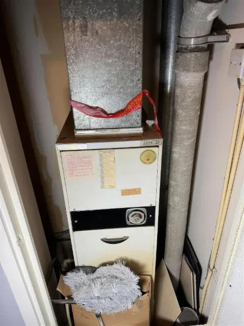 Old warm air heater unit with its galvanised flue duct, taped off ready for removal