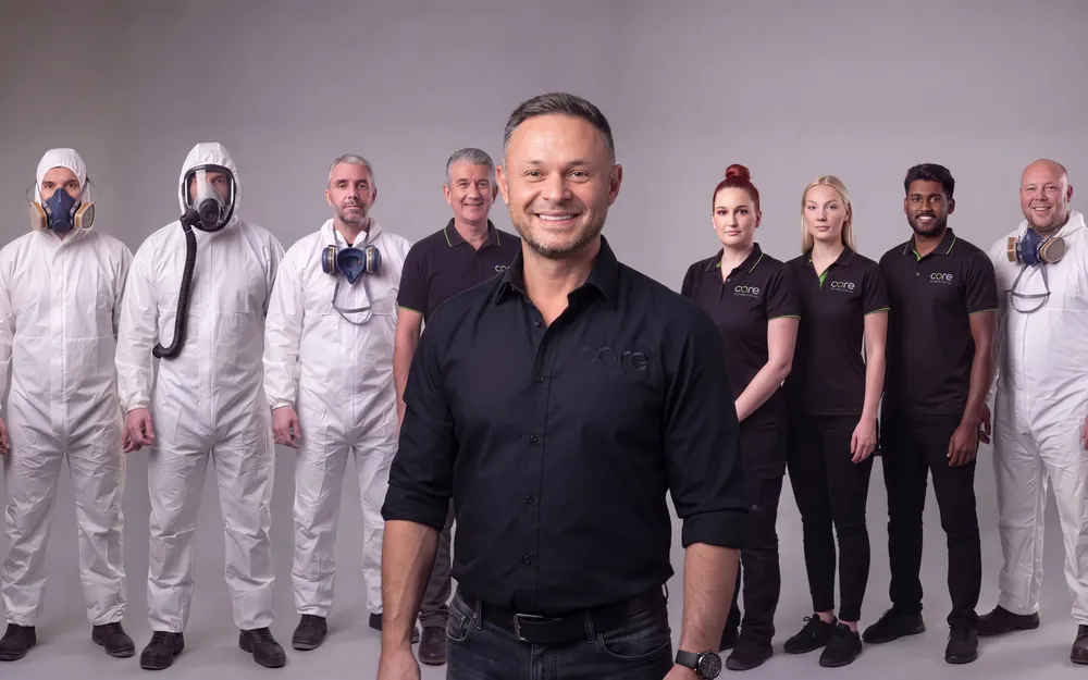 The Core Asbestos Services team: removal operatives in protective coveralls and respirators alongside surveying and office staff